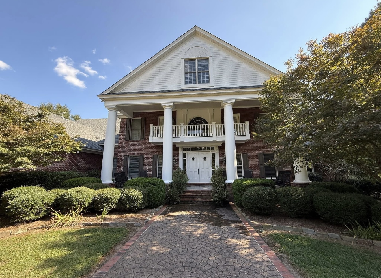 Brick colonial home with dingy siding and stained stamped-concrete driveway before washing in Columbus, GA